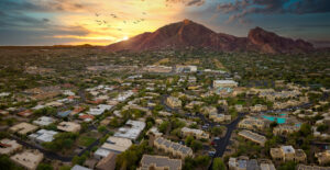 Aerial image of Camelback mountain in Scottsdale Arizona and surrounding homes, resorts, and other commercial buildings at sunset.